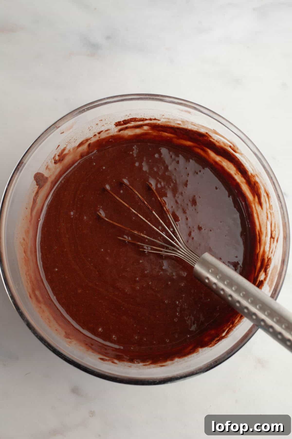 Decadent Chocolate Cupcakes with Cream Cheese Frosting 6 A large glass bowl with chocolate cake batter in it and a whisk.
