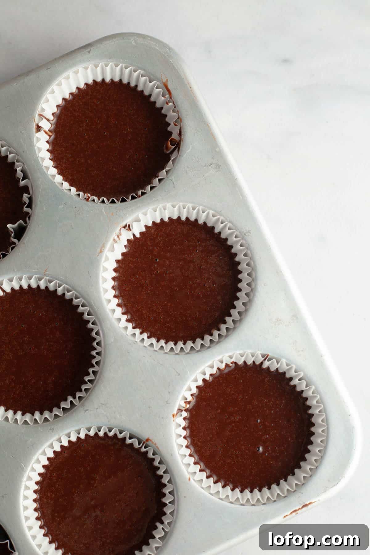 Decadent Chocolate Cupcakes with Cream Cheese Frosting 7 Unbaked chocolate cupcakes in a cupcake pan.
