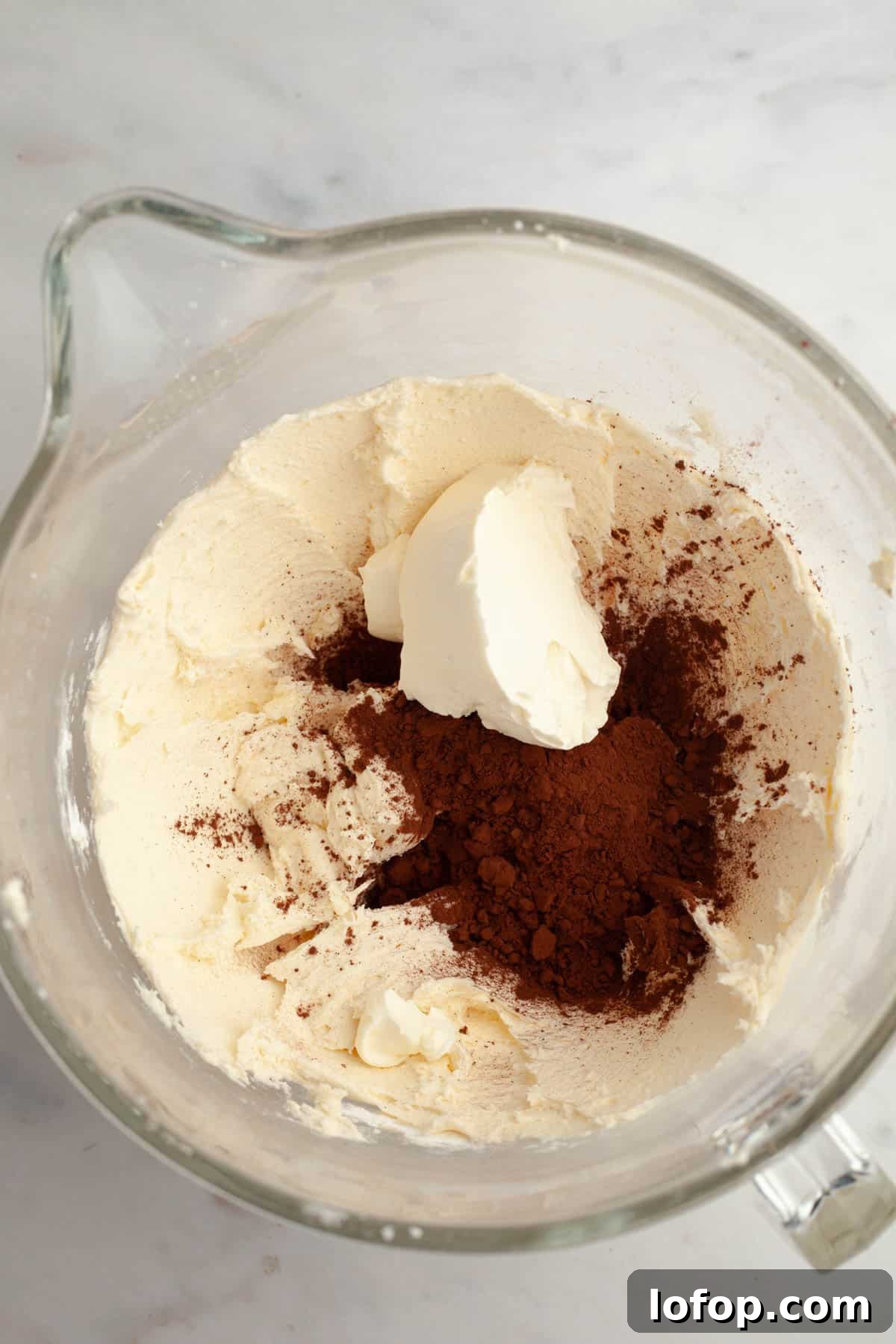 Decadent Chocolate Cupcakes with Cream Cheese Frosting 8 A large mixing bowl with creamed butter in it and cocoa powder and cream cheese.
