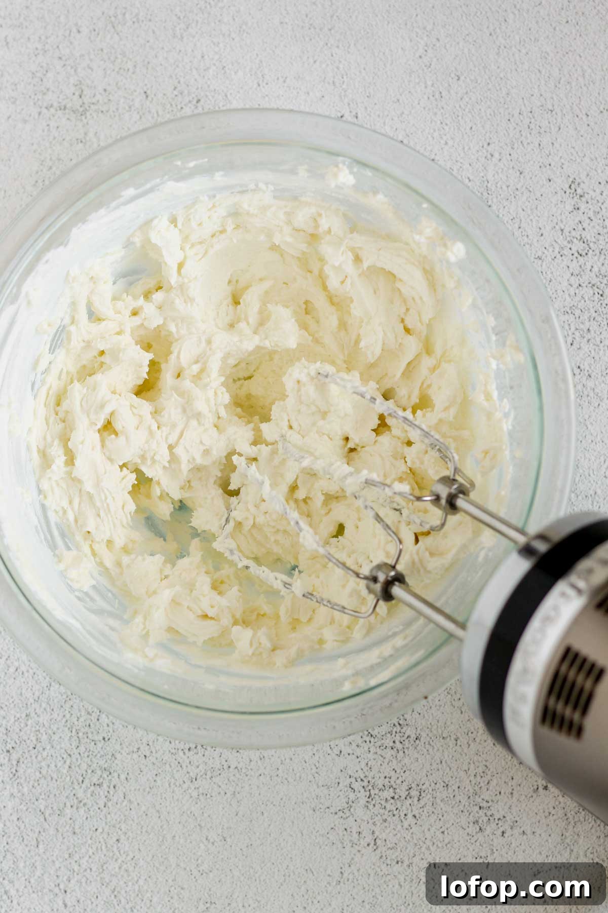 Whipped Goat Cheese and Honey Dip — 5-Ingredient Recipe 4 Goat cheese and yogurt whipped in a glass mixing bowl with a hand-held mixer in the bowl.
