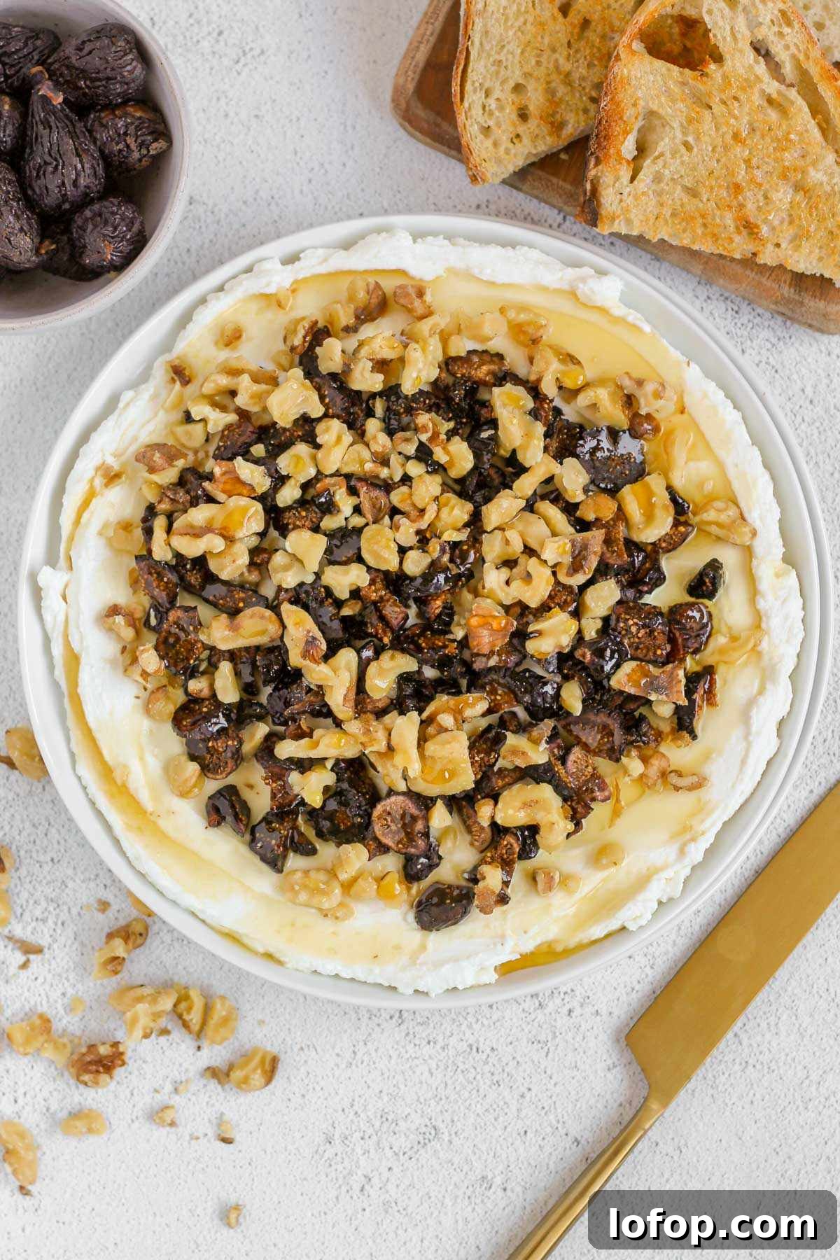 Whipped Goat Cheese and Honey Dip — 5-Ingredient Recipe 8 Whipped goat cheese topped with honey, sliced dried figs and walnuts on a small round plate with toast and a gold knife on the side.
