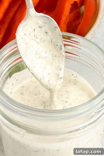 Spoon dripping with ranch dressing.