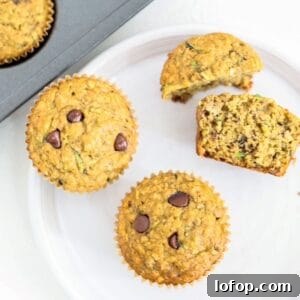 Two whole and two half banana zucchini chocolate chip muffins on a white plate.
