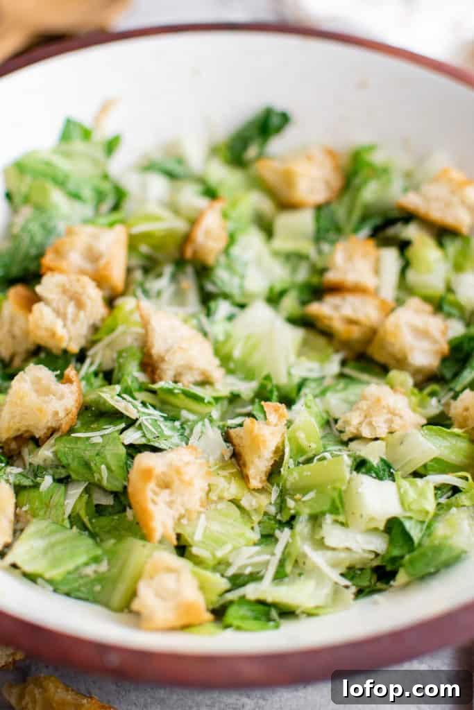 Close up view of Caesar salad with dressing and croutons.