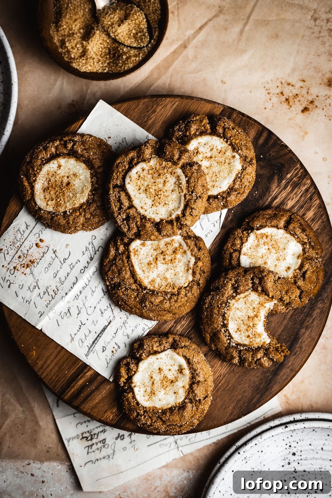 Pumpkin cookies with cream cheese filling on a round wood cutting board. 