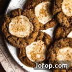 Pumpkin cookies with cream cheese centers on a white speckled ceramic platter.