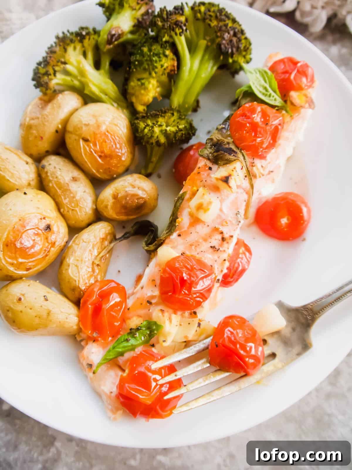 Salmon and tomatoes on a plate with potatoes.