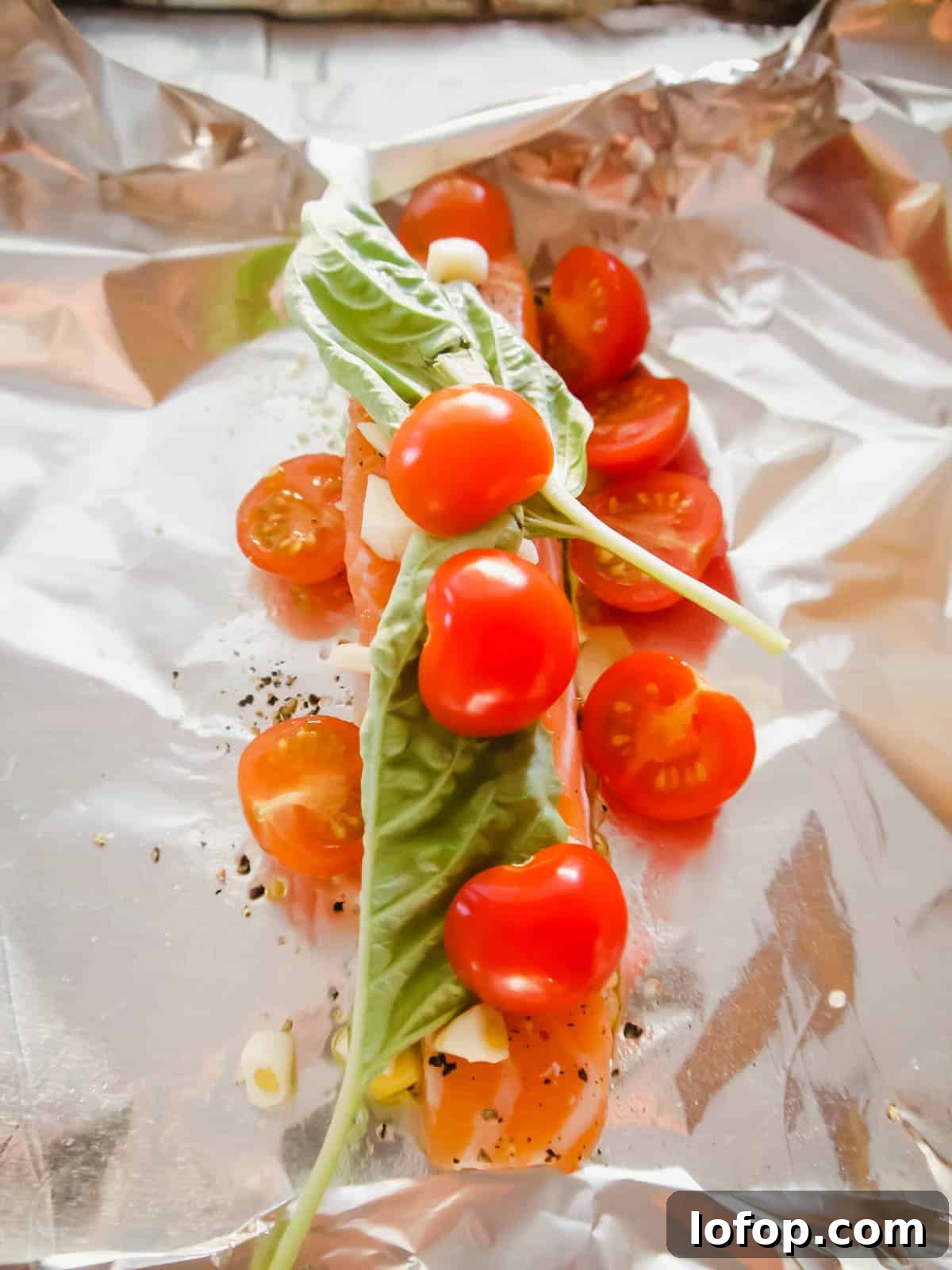 Salmon with garlic, basil, and cherry tomatoes on top.