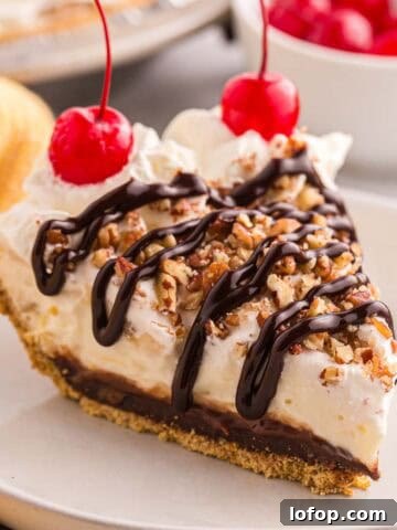 Slice of banana split pie topped with whipped cream, chopped pecans, chocolate syrup, and cherries.