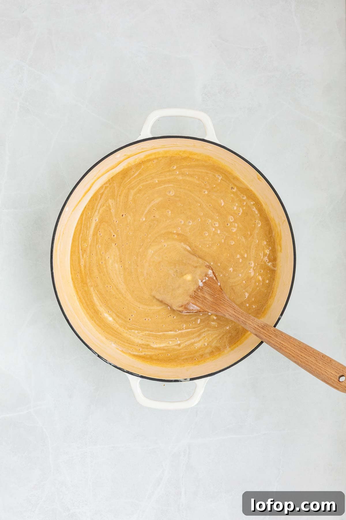 Chocolate Peanut Butter Rice Krispie Treat Recipe 5 Creamy peanut butter mixed into the melted marshmallow mixture inside a pot, stirred with a wooden spatula.