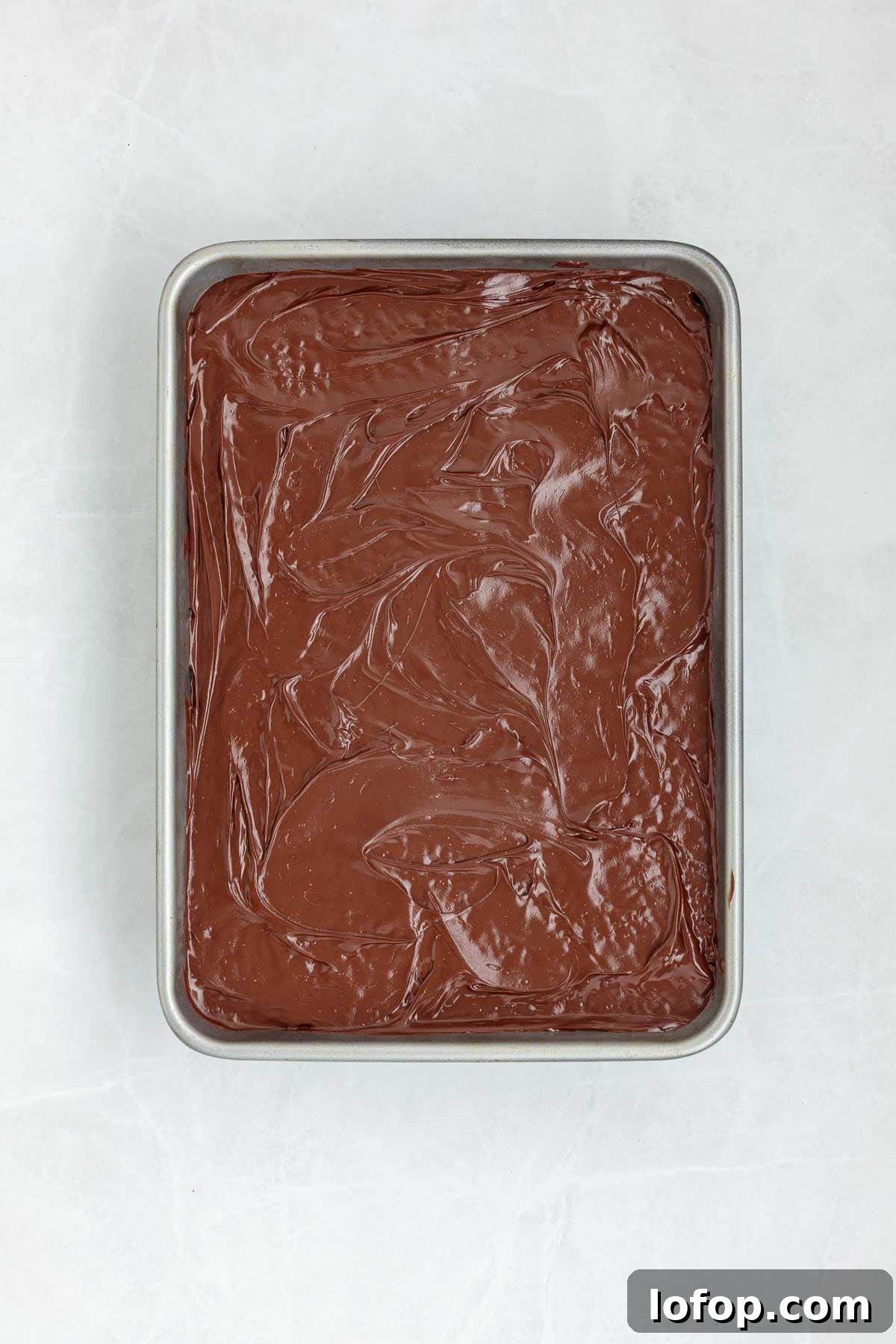 Chocolate Peanut Butter Rice Krispie Treat Recipe 8 Top view of a baking tray with a smooth layer of melted chocolate spread over the Rice Krispie treat base.