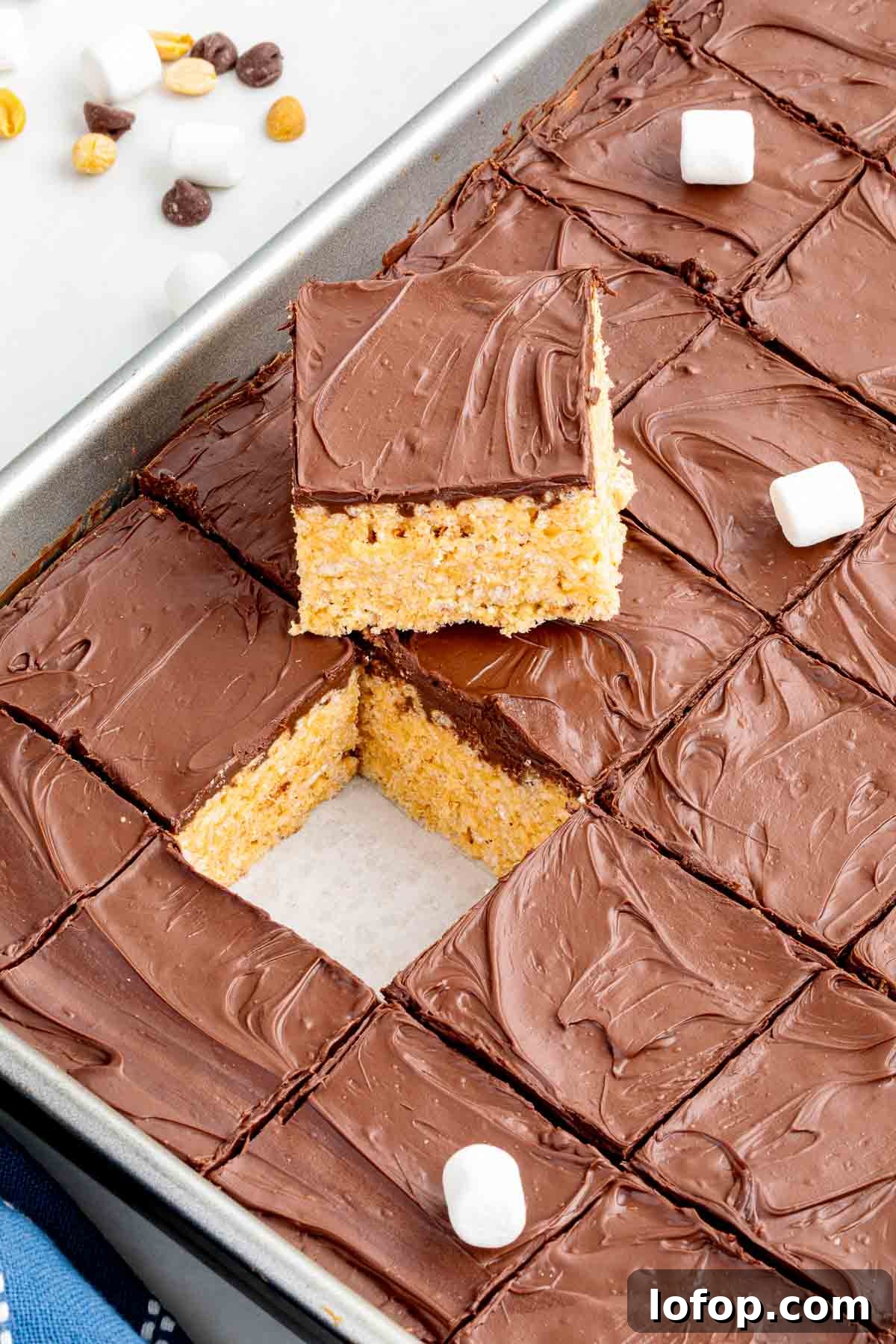 Chocolate Peanut Butter Rice Krispie Treat Recipe 9 Tray of sliced chocolate-topped Rice Krispie treats with one square lifted out, revealing the crispy peanut butter base underneath.