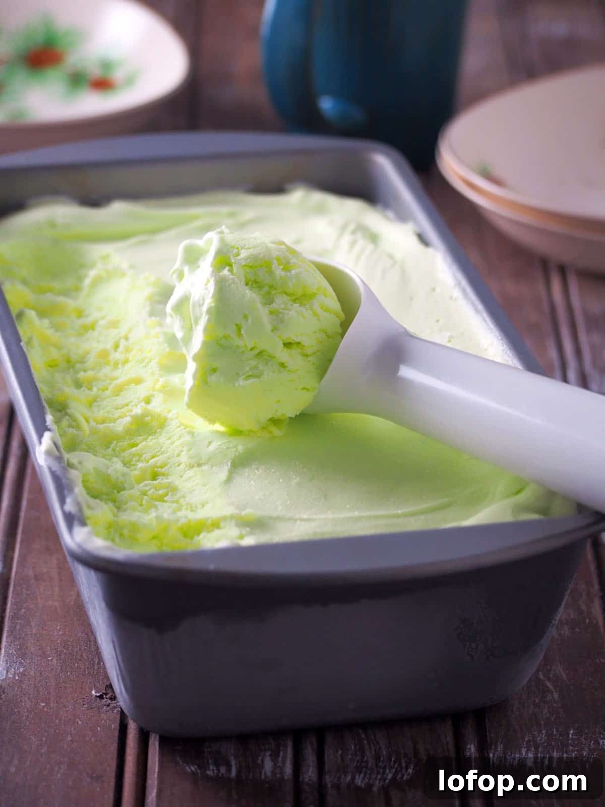 scooping buko pandan ice cream from a metal loaf pan