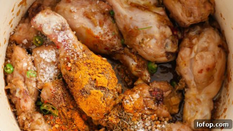 Sautéed chicken in a dutch oven with ground spices and sliced green chillies.