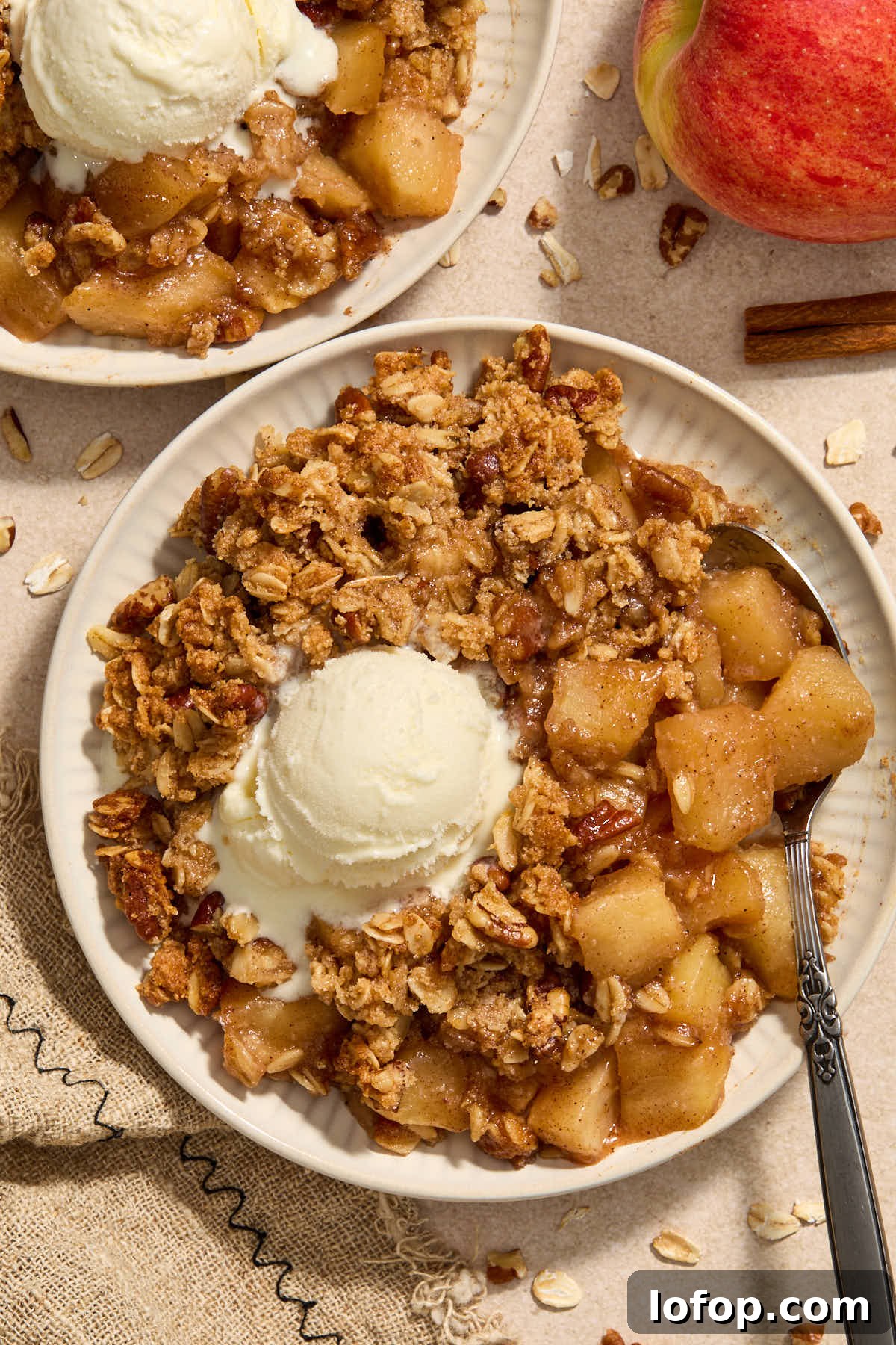 Apple crisp on a plate with vanilla ice cream on top.