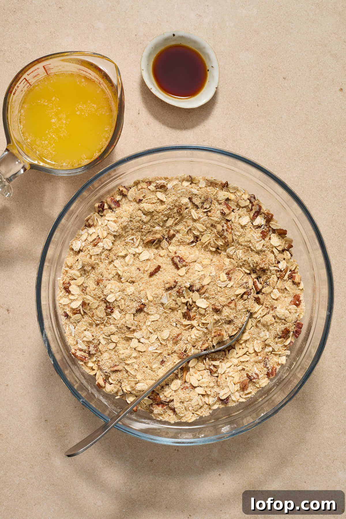 Dry crisp ingredients stirred together in a glass bowl with melted butter and vanilla on the side.