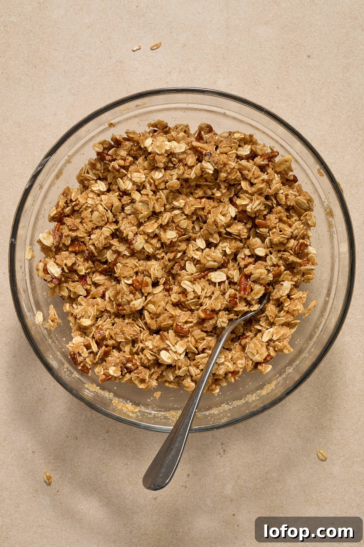 Crisp topping mixed together in a glass bowl with a fork.