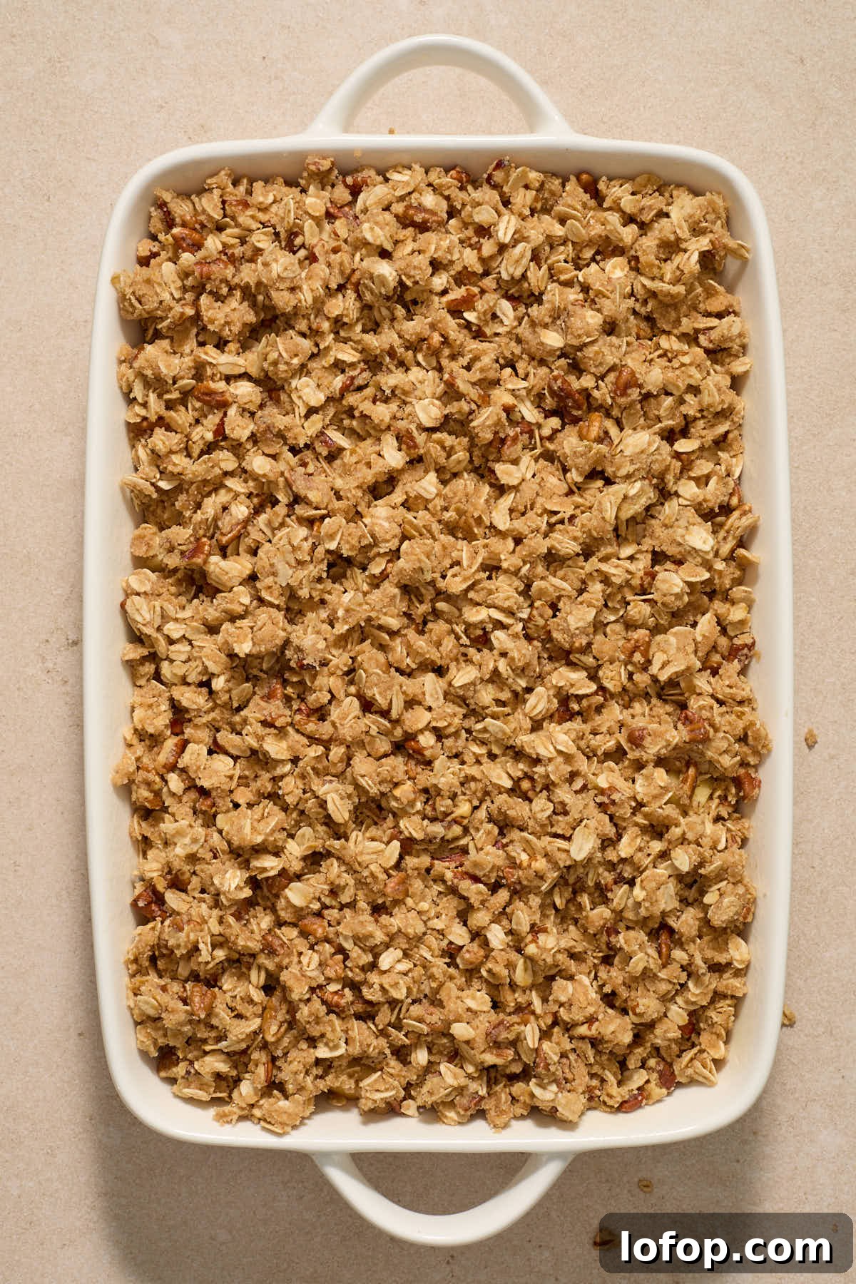 Crisp topping layered on top of apples in baking dish.