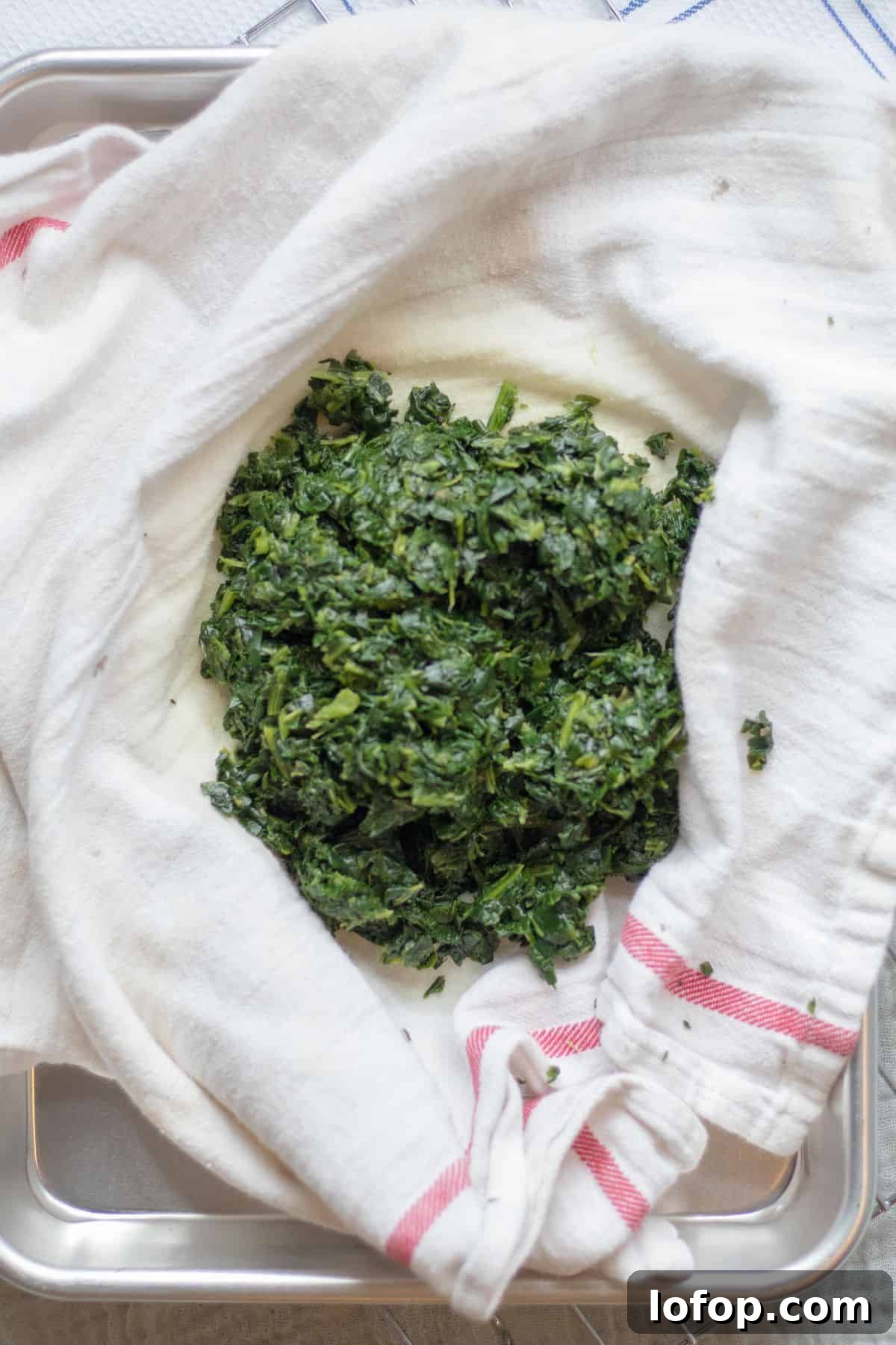 squeezing spinach out in a kitchen towel.