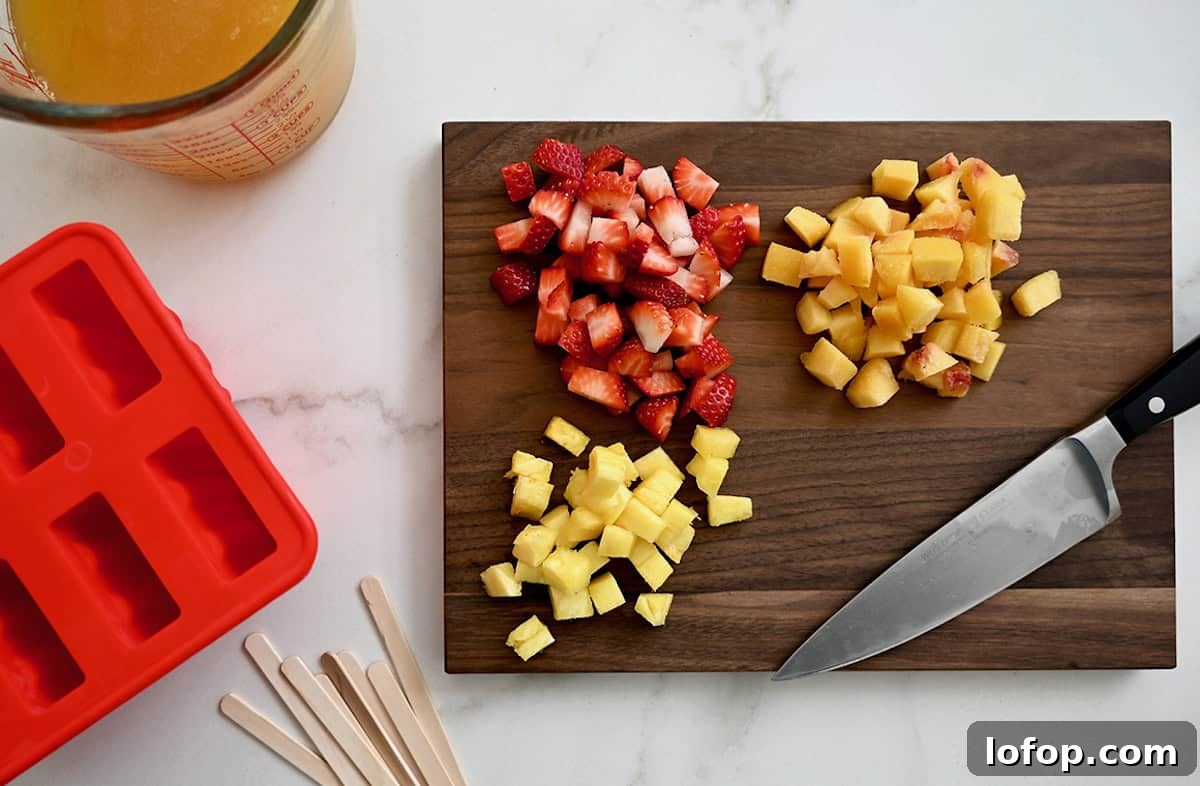 Peach Sangria Popsicles Recipe: Refreshing Boozy Summer Treat 3 Chopped peaches, strawberries and pineapple on a wooden cutting board.