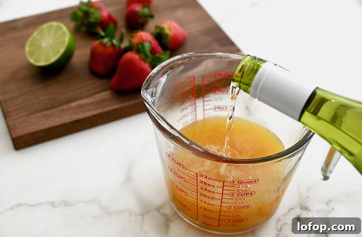 Peach Sangria Popsicles Recipe: Refreshing Boozy Summer Treat 4 White wine being poured into a measuring cup containing peach juice.