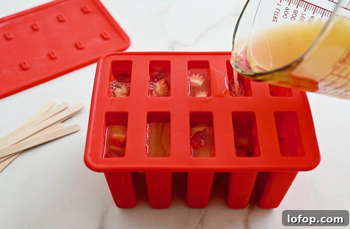 Peach Sangria Popsicles Recipe: Refreshing Boozy Summer Treat 5 A person using a measuring cup to fill a popsicle mold with peach sangria popsicle mix.