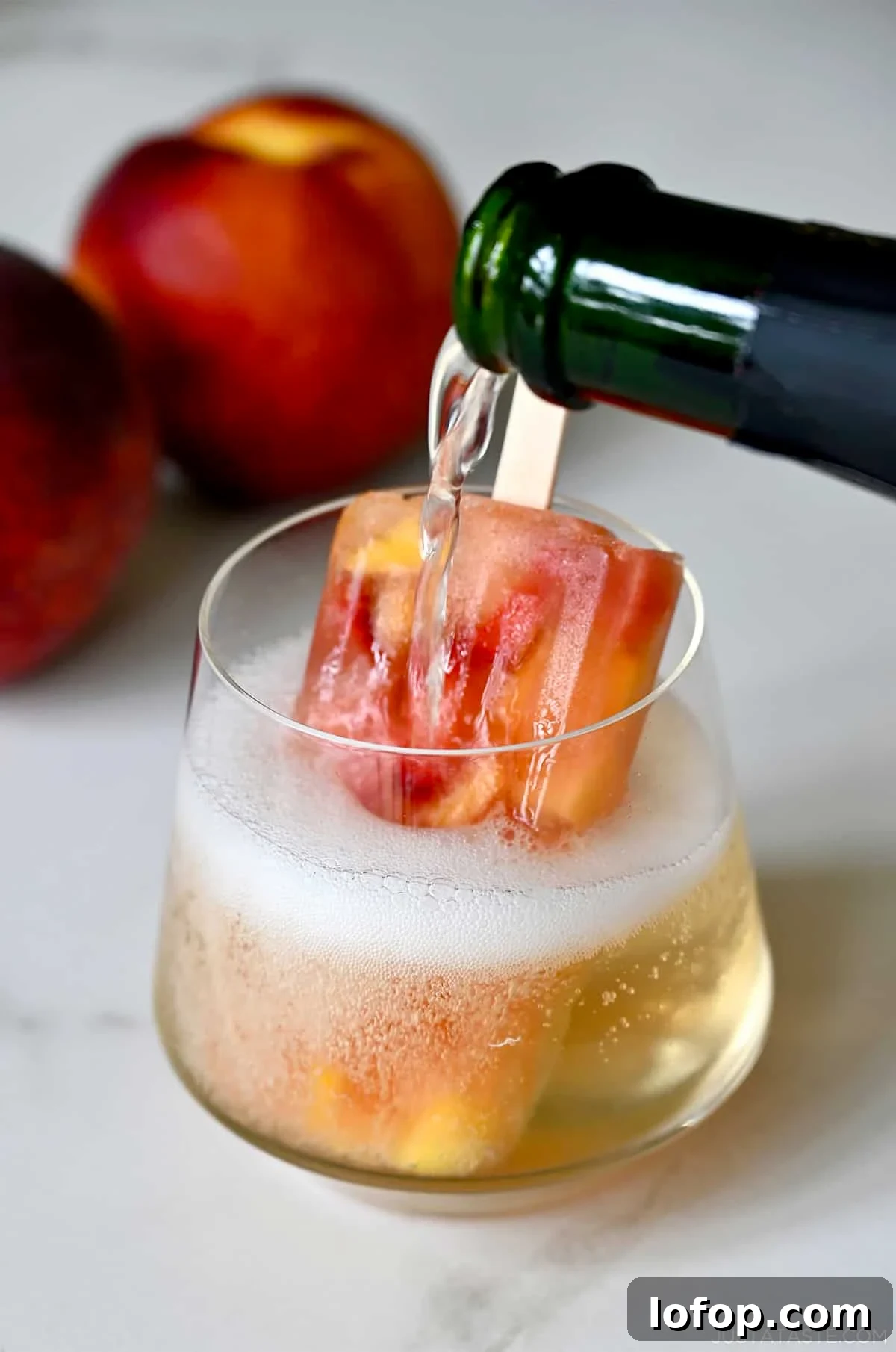 Peach Sangria Popsicles Recipe: Refreshing Boozy Summer Treat 6 Peach sangria popsicle served in a wine glass topped with bubbly prosecco.