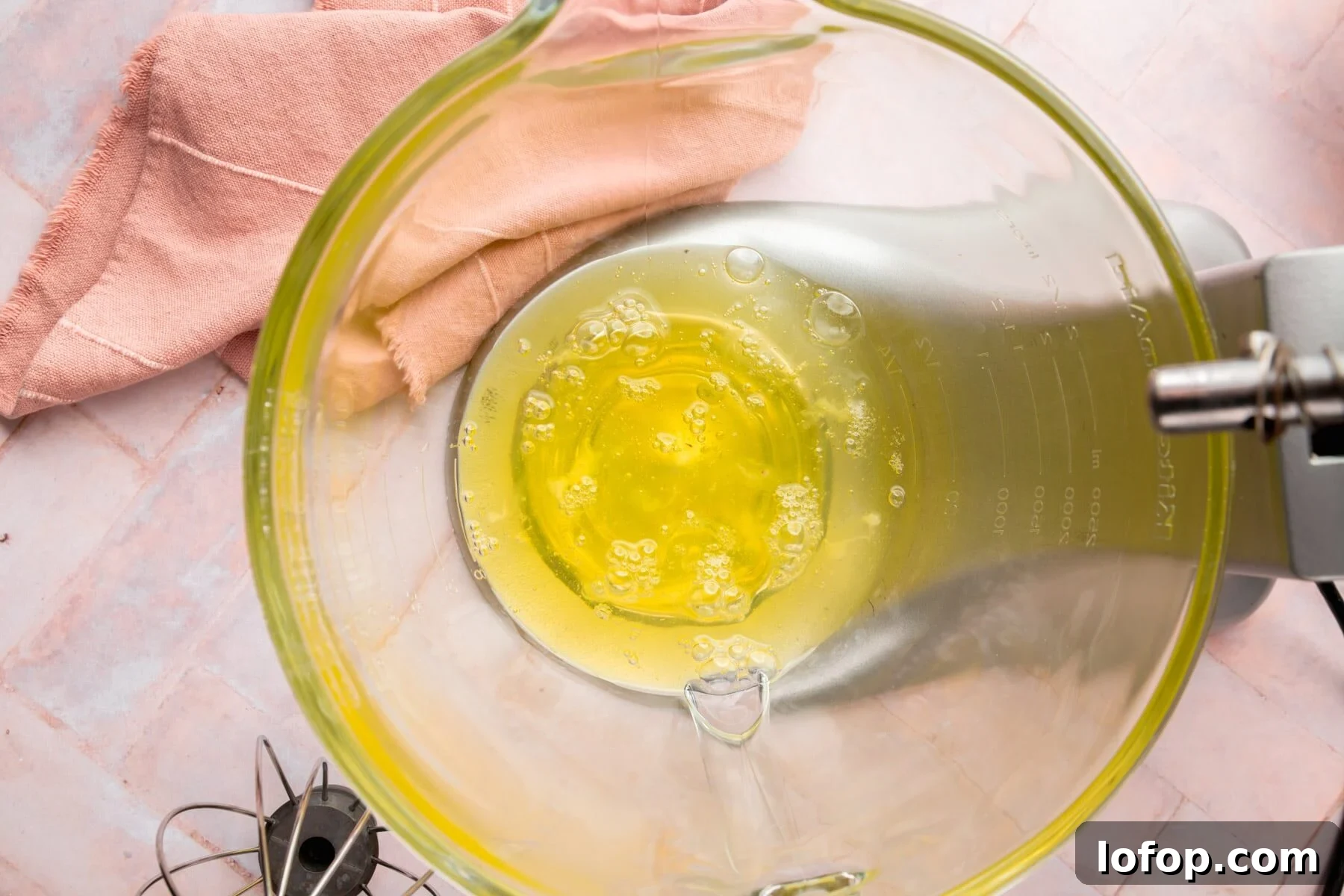 Egg whites in a glass mixing bowl of a stand mixer.