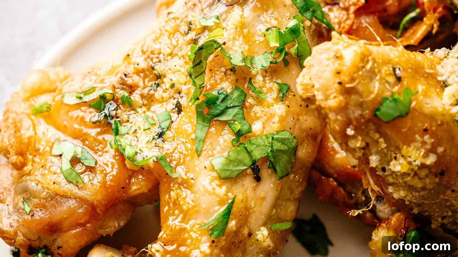 31 Budget-Friendly Winter Meals to Stretch One Grocery Trip Into a Week 12 Close-up of seasoned baked chicken wings garnished with chopped fresh parsley on a white plate.