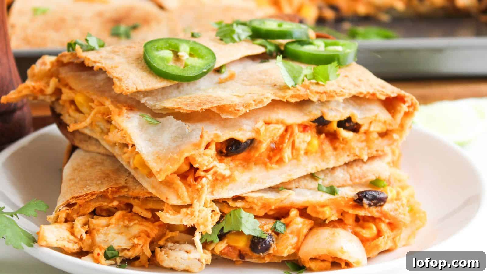 31 Budget-Friendly Winter Meals to Stretch One Grocery Trip Into a Week 16 Close-up of stacked quesadilla slices filled with cheese, beans, and chicken, topped with sliced jalapeños and cilantro, on a white plate.