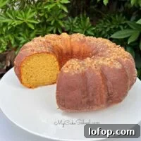 Moist Eggnog Rum Cake, sliced, on a white pedestal.