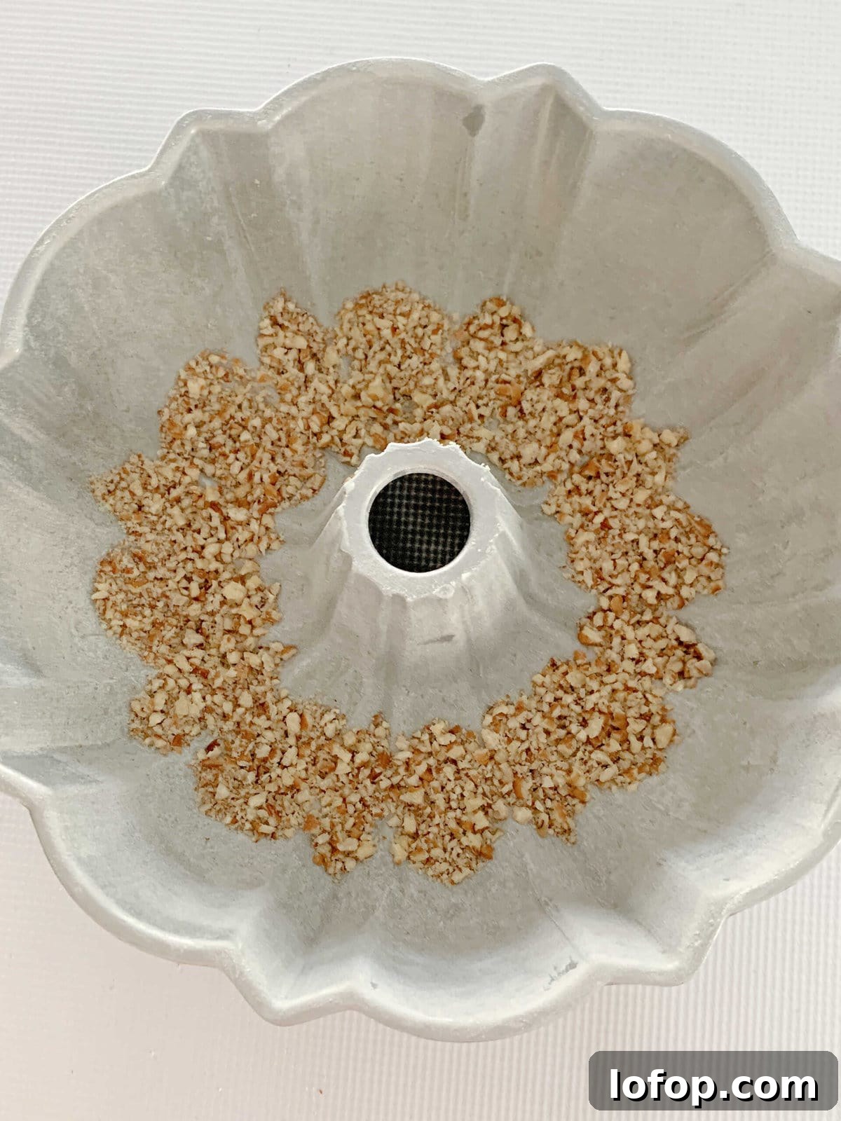 Crushed pecans at the bottom of a prepared bundt pan.