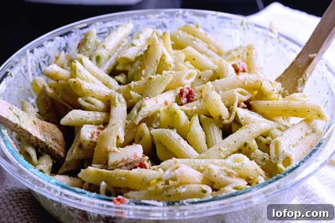 Creamy Pesto Pasta Salad Made with Store-Bought Pesto 7 combining creamy pesto pasta salad with mozzarella, sun-dried tomatoes and with store bought pesto