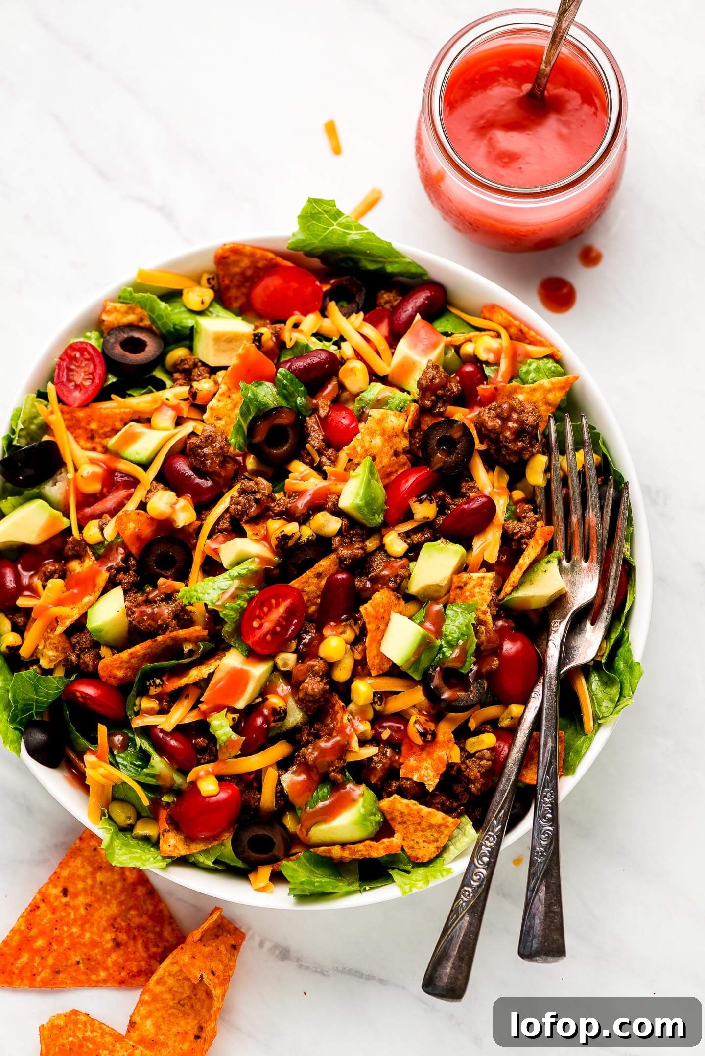 Crispy Dorito Taco Salad Recipe for Game Day and Weeknight Meals 10 Taco Salad dizzled with Catalina dressing and a jar of it to the side.