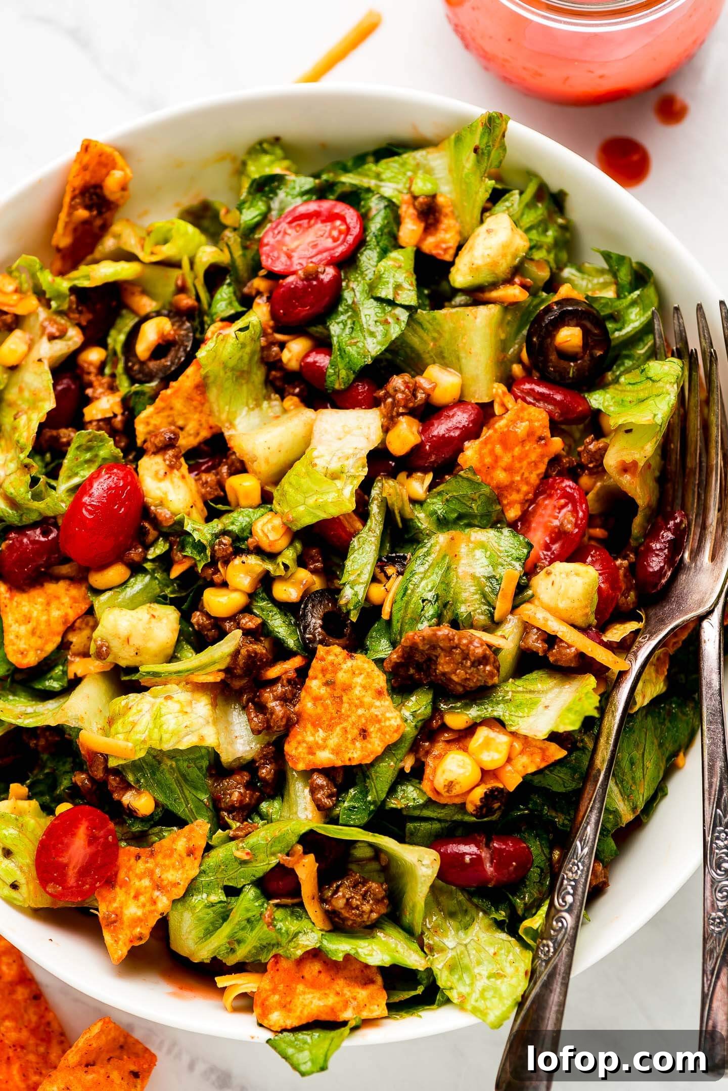 Crispy Dorito Taco Salad Recipe for Game Day and Weeknight Meals 9 Dorito Taco Salad in a bowl tossed in dressing.