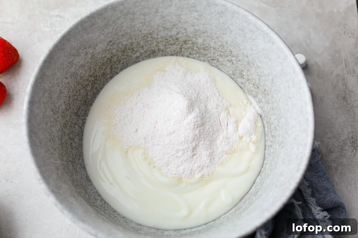 Mixing bowl with vanilla yogurt and pudding mix added to it. 