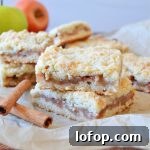 Apple Crumble Bars with Cinnamon Streusel 6 two apple crumble bars stacked on parchment paper with cinnamon sticks