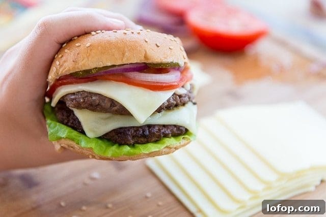 Double Decker Burger Recipe: How to Build a Juicy Stacked Burger 2 A Double Decker Burger Held up with Hand Over Cutting Board