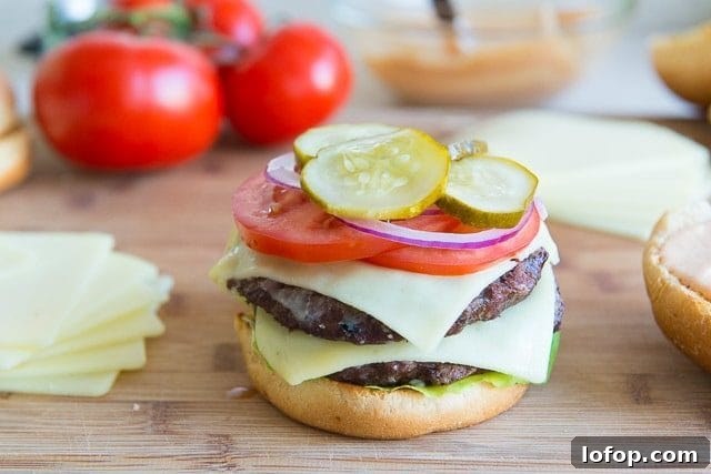 Double Decker Burger Recipe: How to Build a Juicy Stacked Burger 11 Pickles, Red Onion, Tomatoes, added to Bun with Two Beef Patties and Cheese Slices