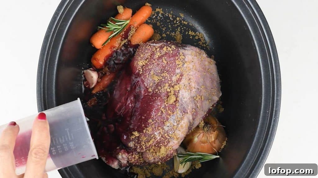 Slow Cooker Leg of Lamb with Garlic and Herbs 6 Slow cooked lamb in a crockpot with vegetables and cooking juices.
