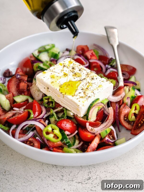 Slow Cooker Leg of Lamb with Garlic and Herbs 9 Greek Salad in a white bowl being drizzled with olive oil