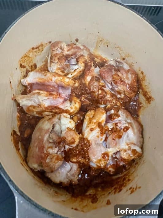 chicken thighs with Thai Red Curry paste in pan