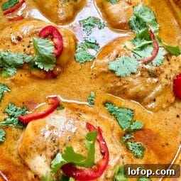 A dish full of chicken thighs in a red Thai sauce