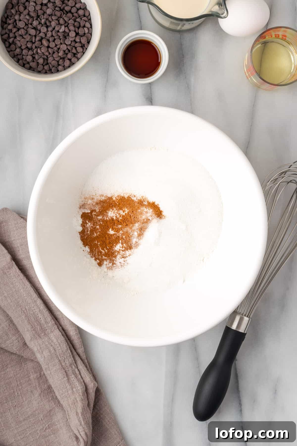 Gluten free flour, sugar, baking powder, salt and cinnamon combined in a large white bowl.