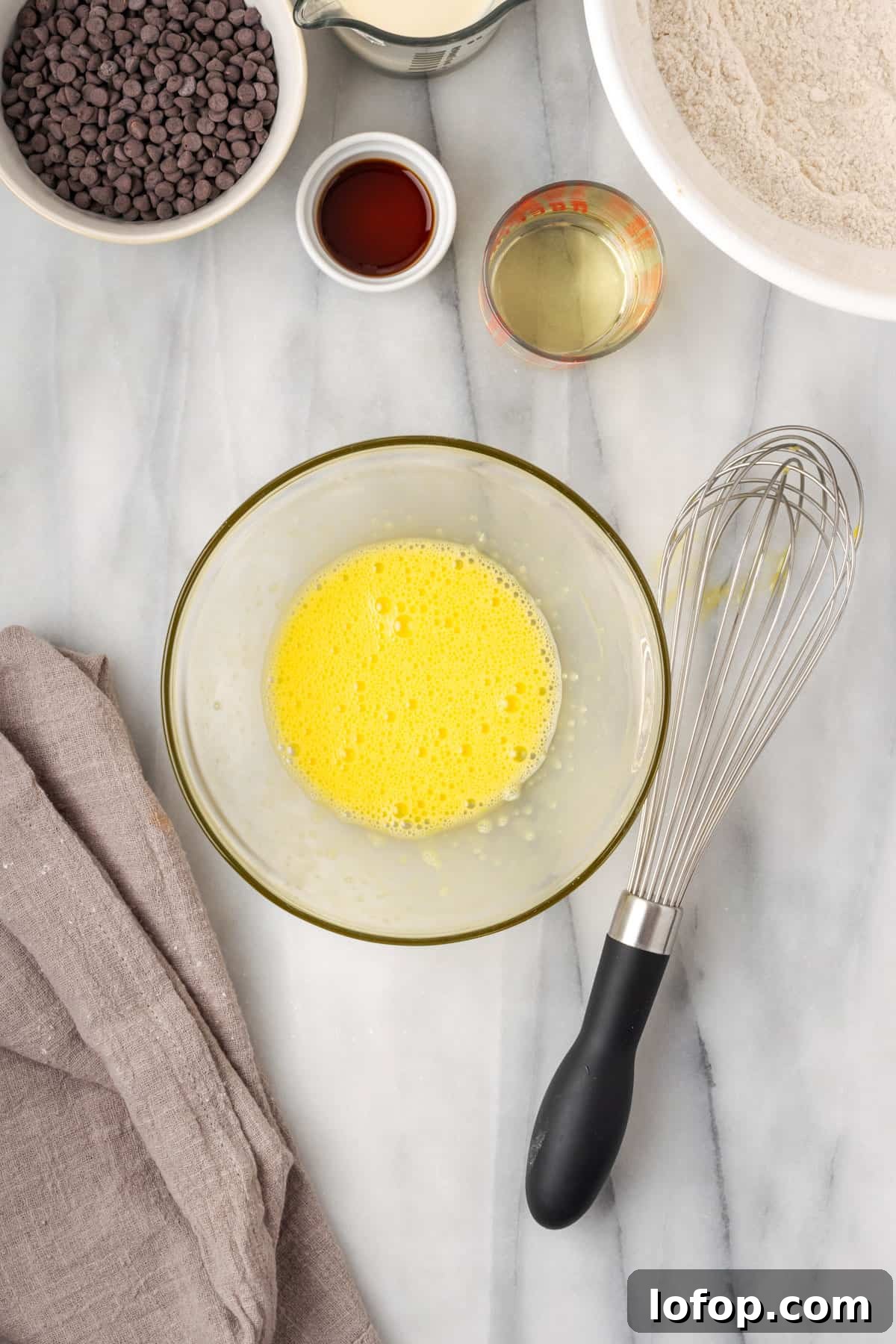 An egg beaten until frothy in a glass bowl.