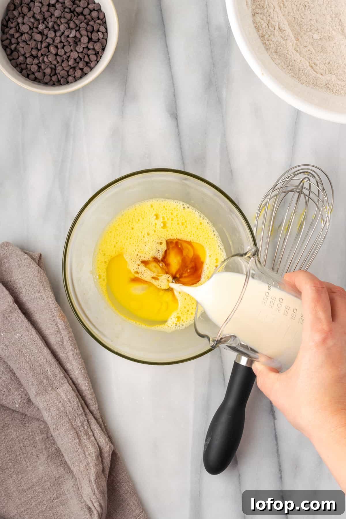 Milk being poured into the bowl with the beaten egg.