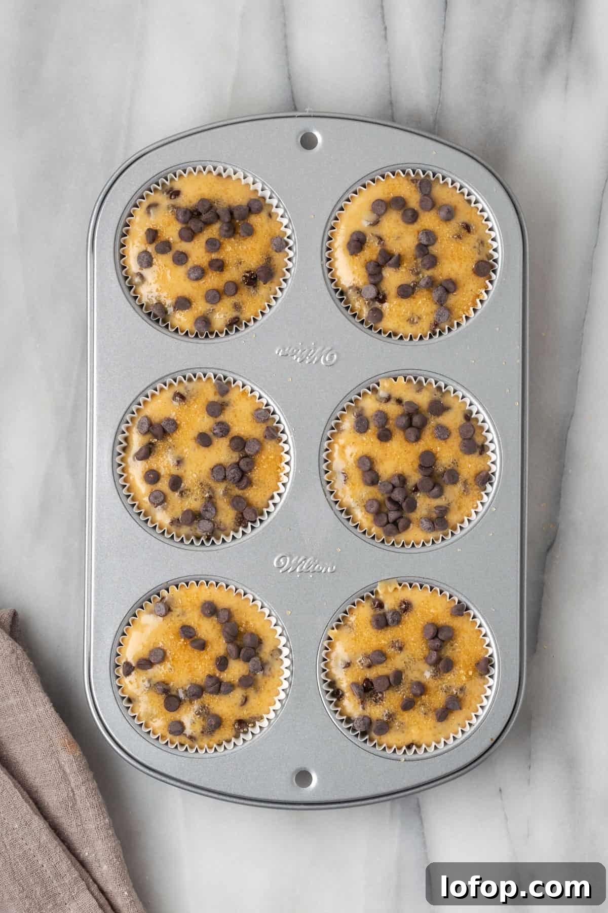 Unbaked gluten free chocolate chip muffin batter in a 6-cup muffin tin.