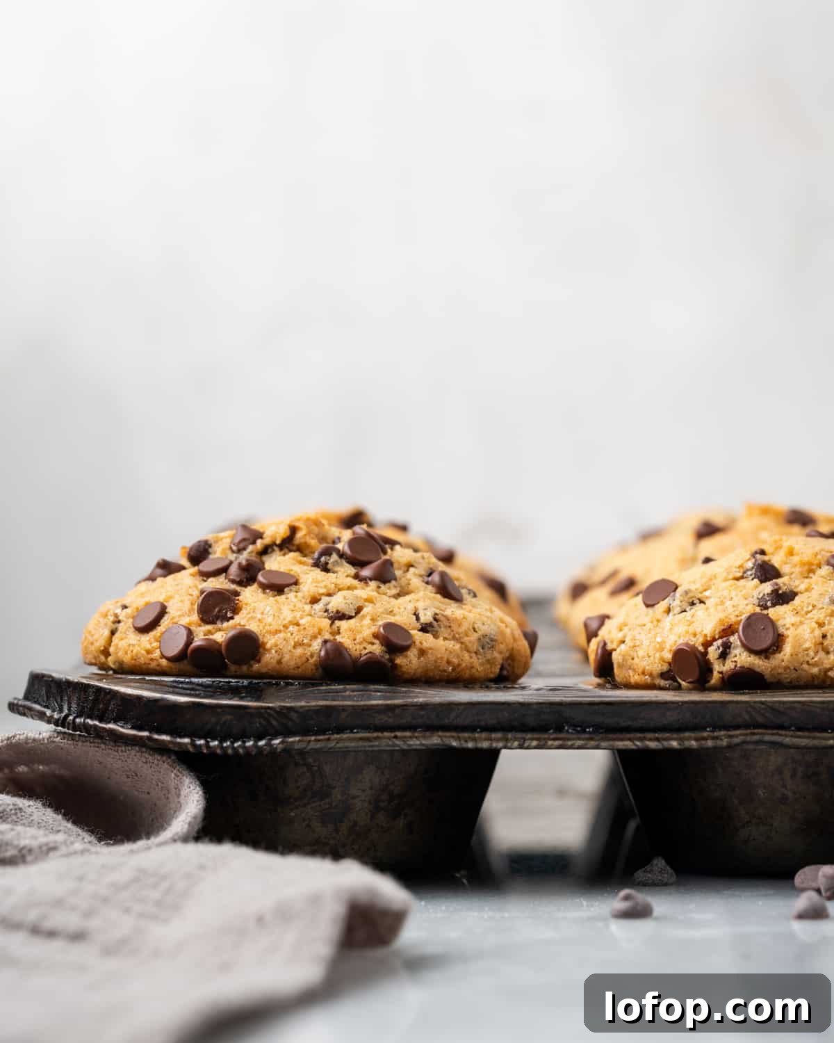 Gluten free chocolate chip muffins in a muffin tin on a marble countertop.
