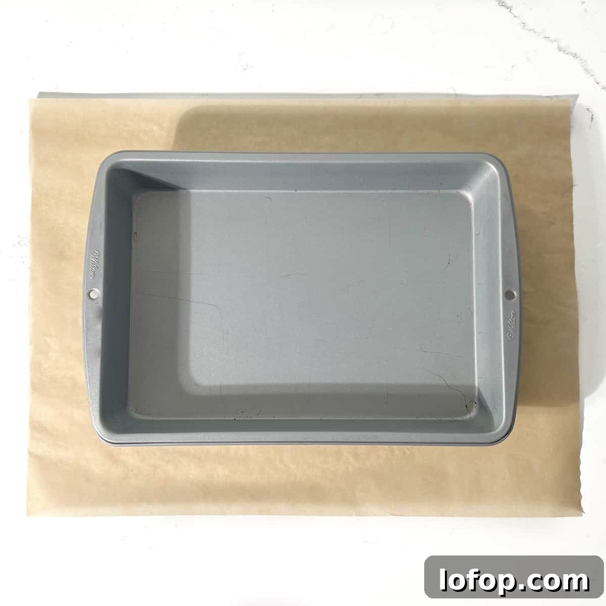 A baking tin on a rectangular piece of baking paper. 