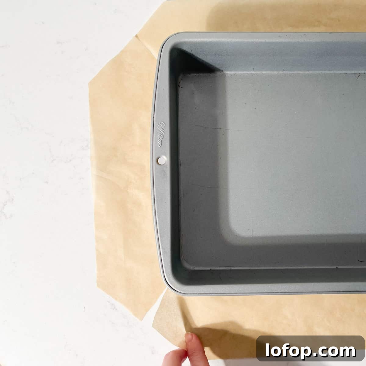 A baking tin on a piece of baking paper with slits cut into each corner of the paper to fit easily into the tin.